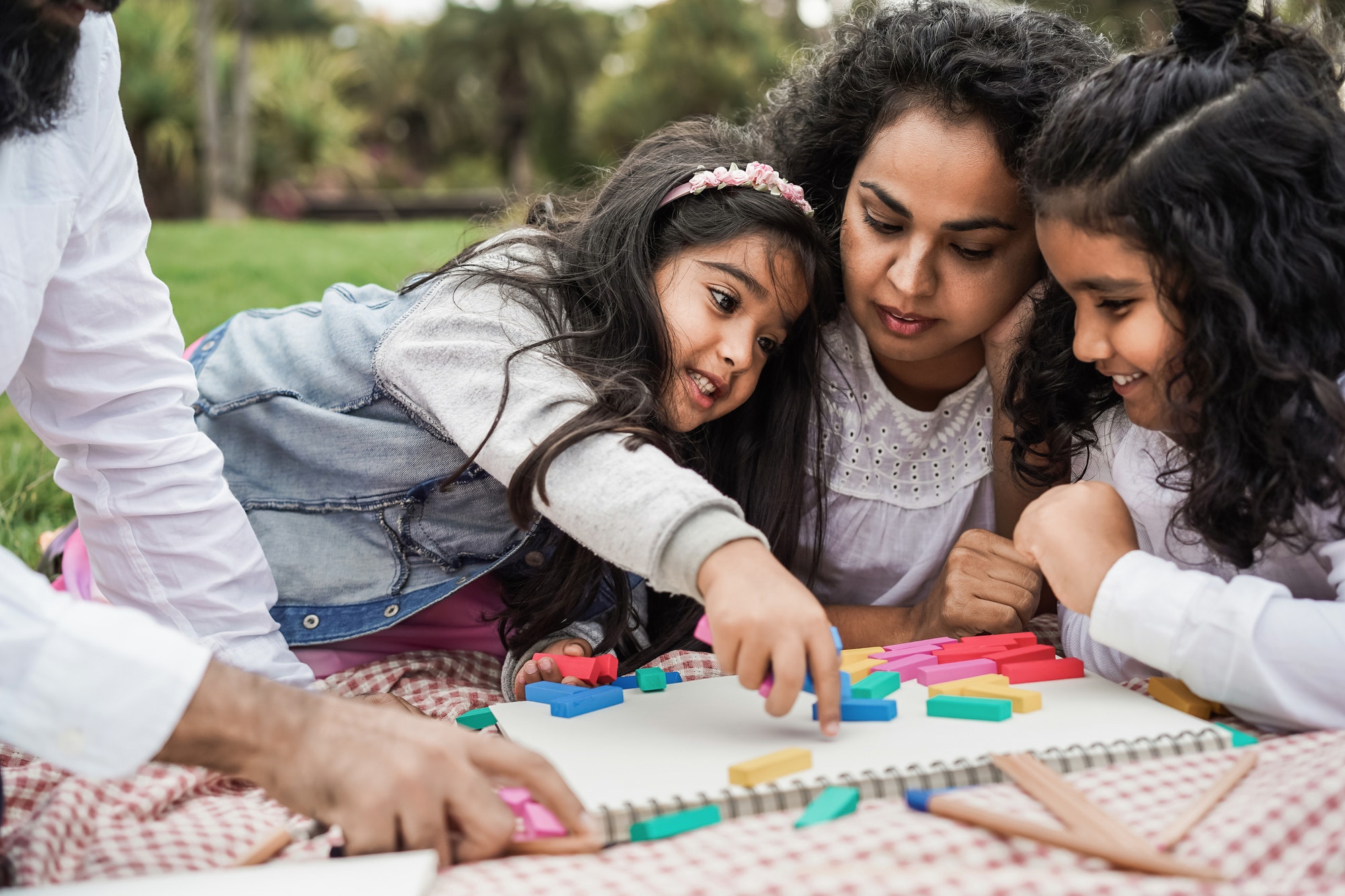 Indian parents having fun at city park playing with wood toys with their daughter and son